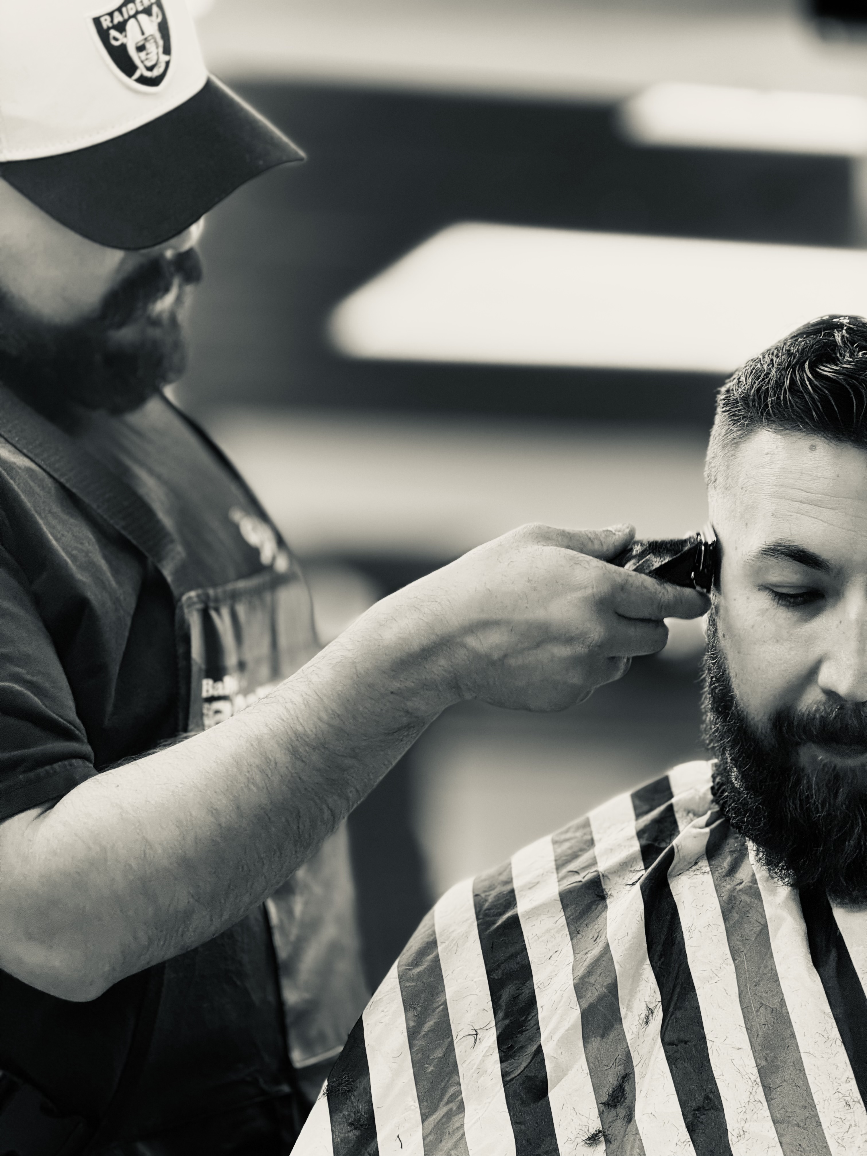 Luis trimming a bearded client's hairline